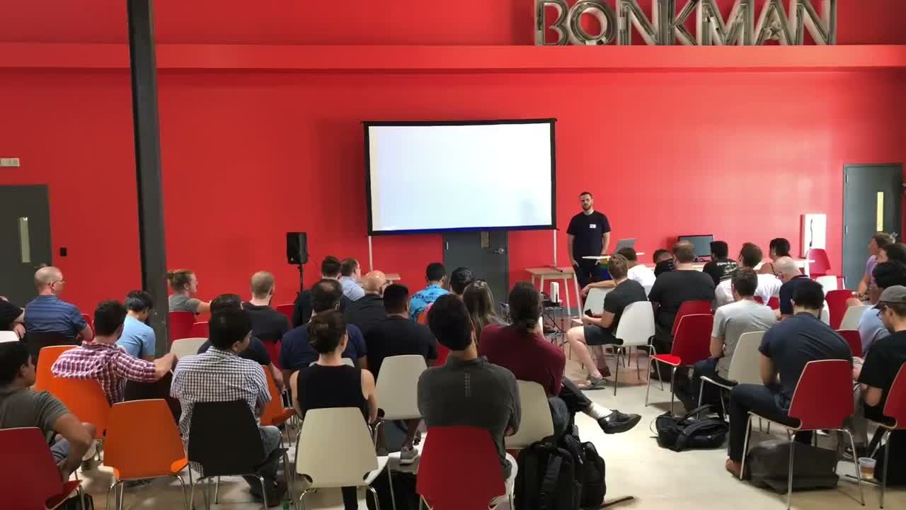 Refactor Camp 2018 Day 1 main room, full audience, red walls