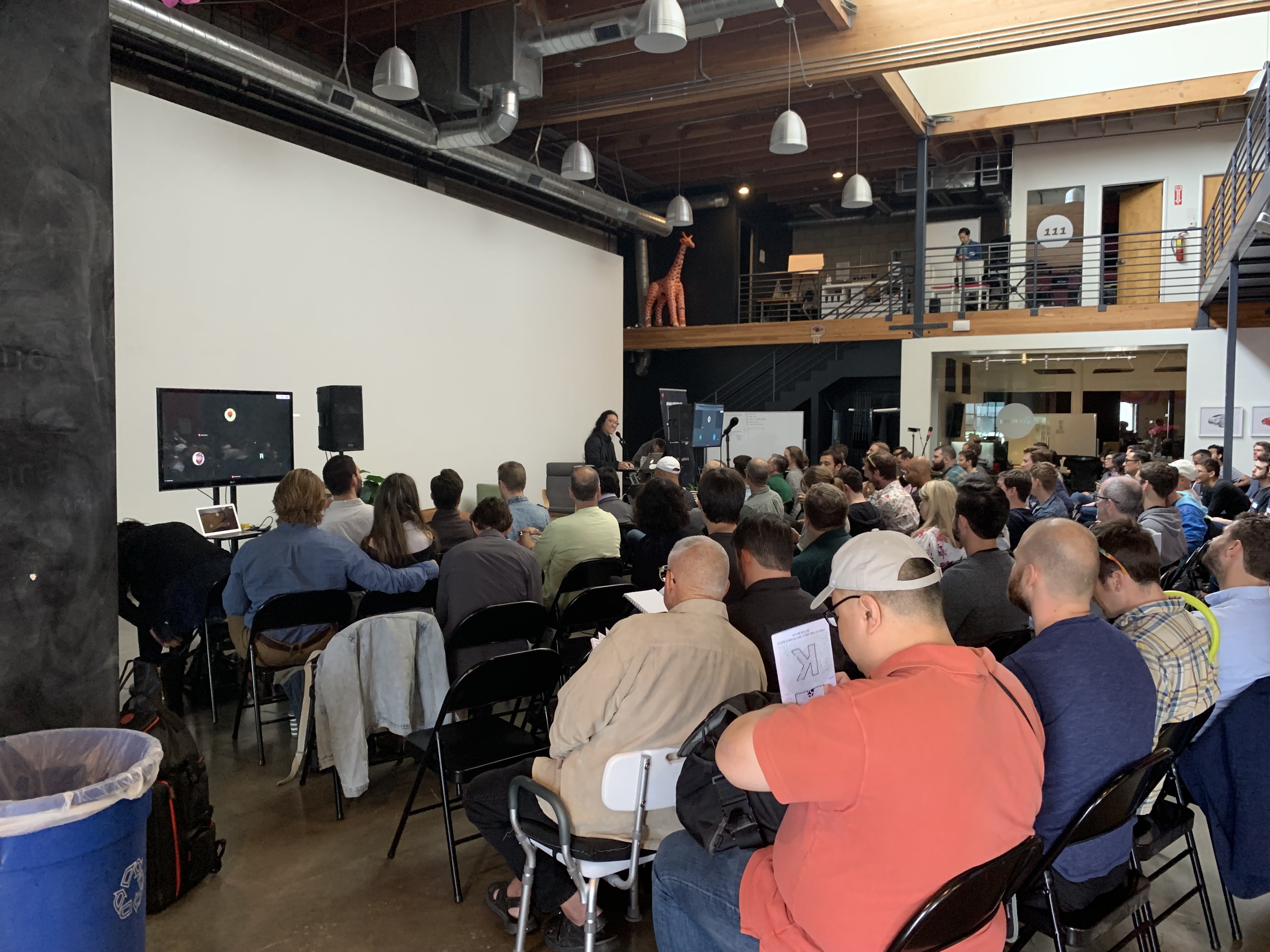 Refactor Camp 2019 main hall audience, giraffe on mezzanine